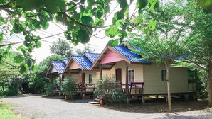 A row of small, single-story cabins with blue roofs and wooden railings, surrounded by greenery. - Ban Chomlay Resort Satun (La-ngu)