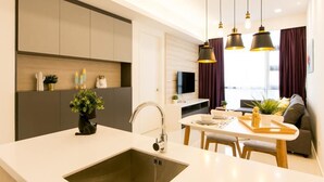A modern kitchen with a central island, a dining area with a table and chairs, and a living space with a sofa and curtains. - The Robertson Suites Bukit Bintang (Kuala Lumpur)
