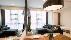 A modern hotel room with a dining area, two sofas, a bed, and large windows. - The Robertson Suites Bukit Bintang (Kuala Lumpur)