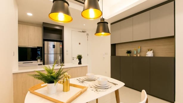 A modern kitchen with a built-in refrigerator, a microwave, and a stove. There is a dining table with a tray, a potted plant, and a gold decorative piece. - The Robertson Suites Bukit Bintang (Kuala Lumpur)