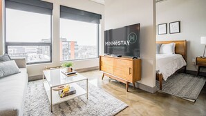 Una habitación de hotel moderna con un televisor grande, una cama, un sofá y una mesita de café.