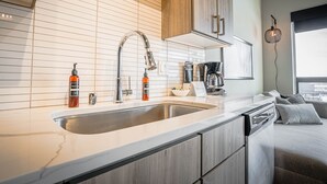 Una cocina moderna con un lavamanos doble, armarios de madera y una cafetera.