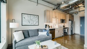 A modern living room with a grey sofa, a white coffee table, and a map on the wall. - MINNeSTAY* Sable 802 Alcove | North Loop | Target Center (Minneapolis)