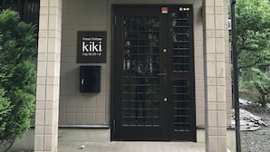 A building with a tiled facade, a black door with a window, and a sign that reads "Forest Cottage KIKI". - Forestcottage kiki. (Fujiyoshida)
