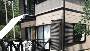 A two-story building with a deck, outdoor seating, and a large window. - Forestcottage kiki. (Fujiyoshida)