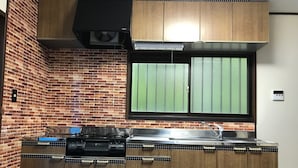 A kitchen with a brick wall, a window, and wooden cabinets. - Forestcottage kiki. (Fujiyoshida)
