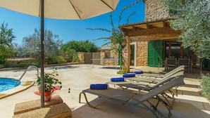 A poolside area with lounge chairs, a covered seating area, and a stone building with green shutters. - Wonderful private villa for 6 people with private pool, A/C, WIFI, TV and terrace (Felanitx)