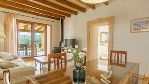 A living room with a wooden ceiling, a dining table with chairs, a sofa, a TV, and a fireplace. - Wonderful private villa for 6 people with private pool, A/C, WIFI, TV and terrace (Felanitx)