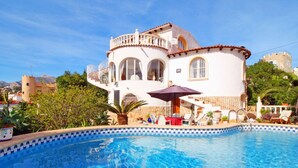 Une grande piscine, avec en arrière-plan un bâtiment blanc doté de fenêtres en arc de cercle et d’un balcon.