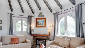 Un salon avec deux canapés, une cheminée et de grandes fenêtres.