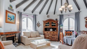 Un salon spacieux avec une cheminée, un meuble en bois et un coin repas avec une table dressée pour deux personnes.