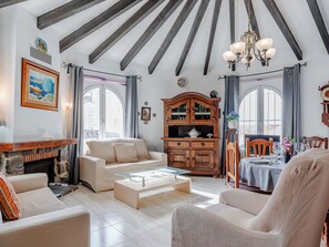 A spacious living room with a fireplace, a wooden cabinet, and a dining area with a table set for two.