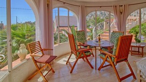 Une pièce baignée de lumière, avec une grande fenêtre, des chaises en bois, une table et une vue sur une colline.