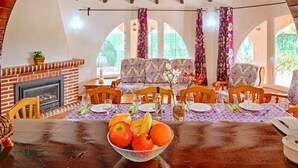 Un comedor con chimenea de ladrillo, muebles de madera y un gran ventanal con cortinas.