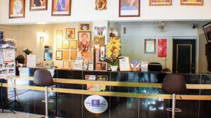 Una recepción con retratos enmarcados, una estatua de Buda y un letrero que dice 'Visit Malaysia 2014'.