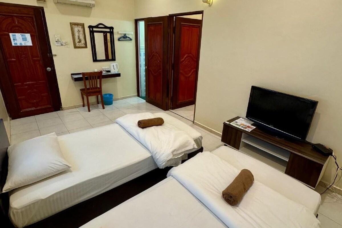 A hotel room with two beds, a television, a desk, and a wardrobe.