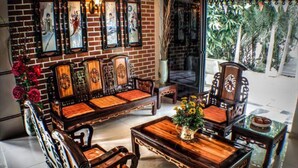 Un salón de estilo tradicional con pared de ladrillo, muebles de madera y un ventanal con vista a palmeras.
