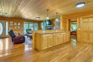L ’intérieur d’un chalet en bois comprend un îlot de cuisine, un plancher en bois et une cheminée.