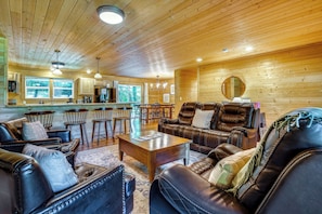 Un intérieur de chalet chaleureux avec des murs en bois, des meubles en cuir, un coin repas et une cuisine.