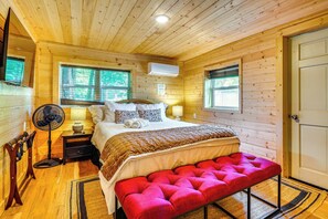 A wooden cabin bedroom with a bed, bedside lamps, a fan, and a bench. - Creekside Smokies Log Cabin w/ Hot Tub & Game Room (Gatlinburg)