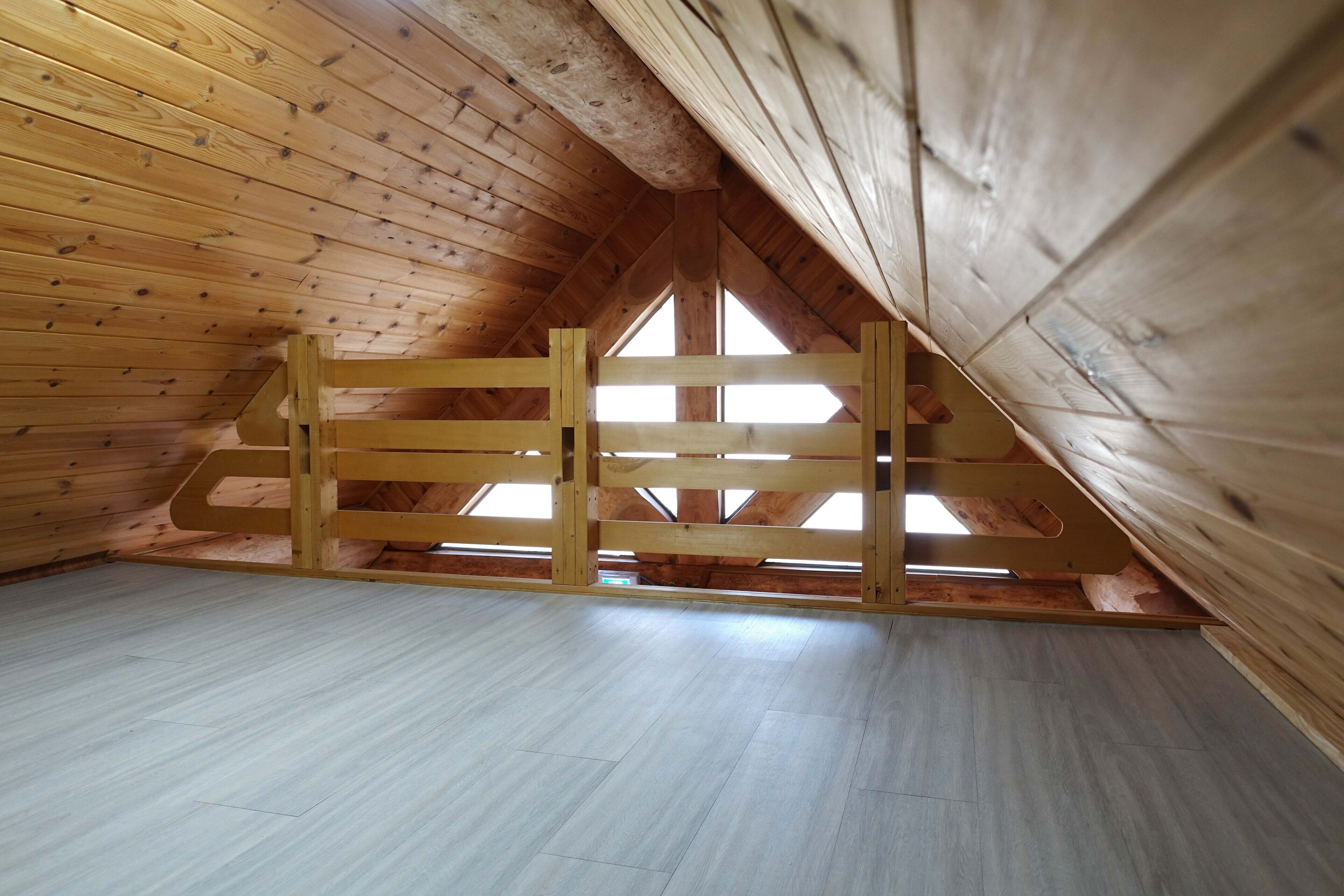 Habitación en el desván con paredes de madera y techo inclinado.