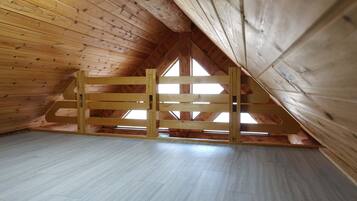 Habitación en el desván con paredes de madera y techo inclinado.