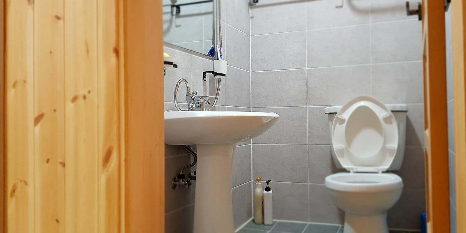 A bathroom with a white sink, a toilet, and a mirror.