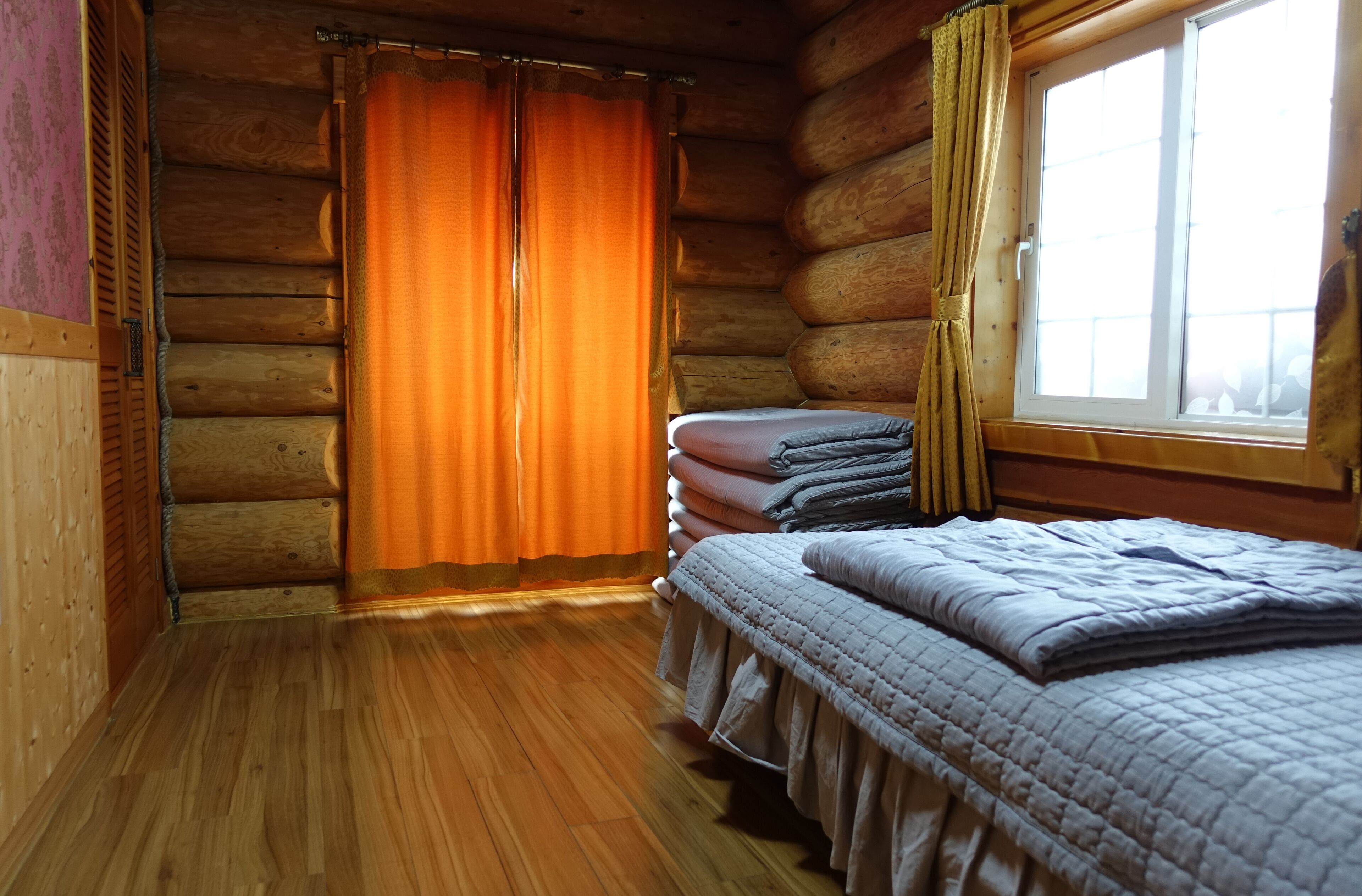 Una habitación tipo cabaña de madera con cama, cortinas y una ventana.