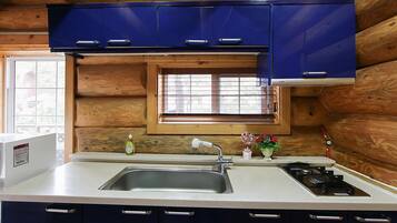 A compact kitchen with a sink, stove, and blue cabinets.
