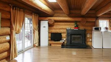 A log cabin interior with a fireplace, a television, and a refrigerator.