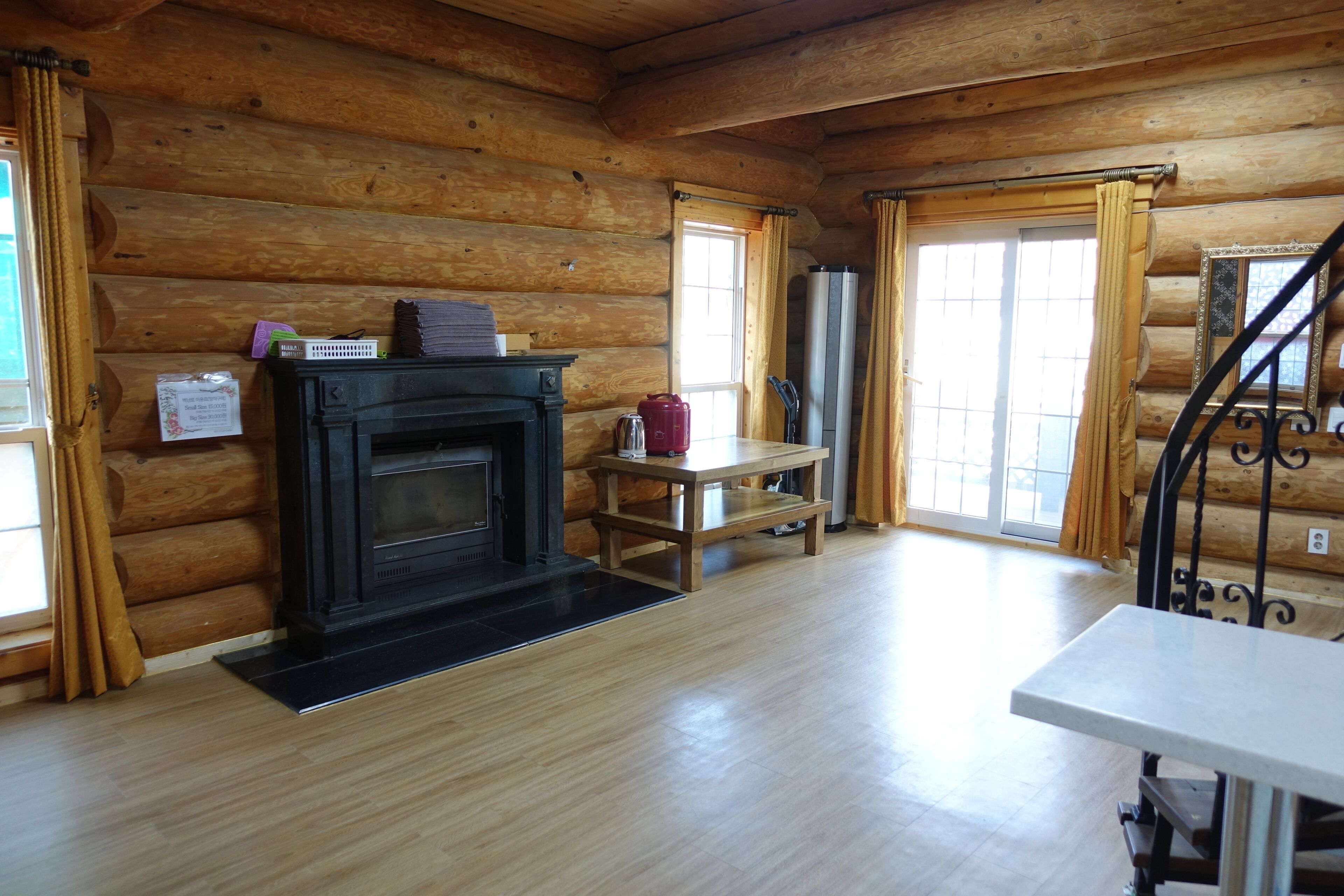 L’intérieur d’une cabane en rondins, avec une cheminée, des murs en bois, une table à manger et un escalier.