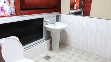 Une salle de bain avec des toilettes blanches, un lavabo et une fenêtre.