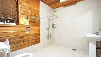 A bathroom with wooden walls, a shower, a sink, and a toilet.