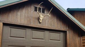 A garage with a wooden exterior and a mounted deer skull with antlers. - Hunting ~n~ Hooks Getaway (Salmon)