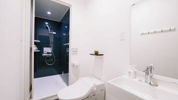 Un baño moderno con inodoro, lavabo y cabina de ducha.