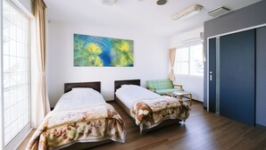 A hotel room with two beds, a large window, a painting, and a door. - Hotel Kailani (Oshima)