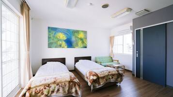 A hotel room with two beds, a large window, a painting, and a door.