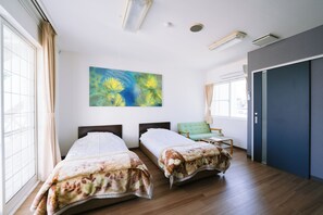Une chambre d’hôtel avec deux lits, une grande fenêtre, un tableau et une porte.