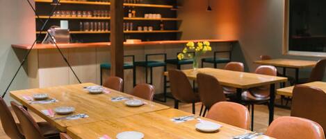 A conference room with a long table, chairs, and a bar area with shelves.