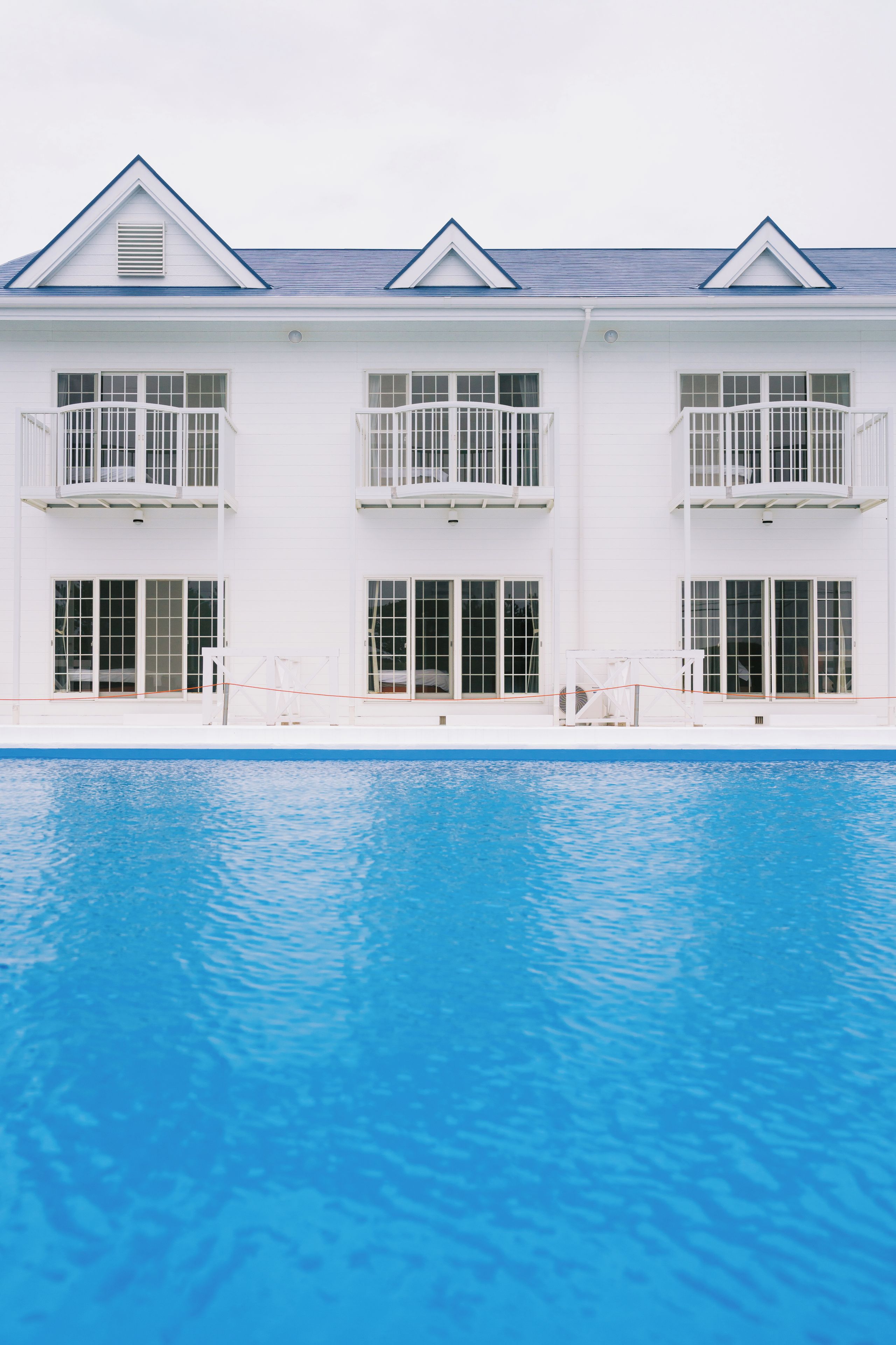 Um edifício de dois andares com piscina em frente.