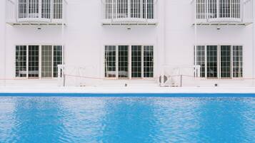Um edifício de dois andares com piscina em frente.