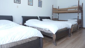 A room with bunk beds and two single beds, white bedding, and framed pictures on the wall. - Hotel Kailani (Oshima)
