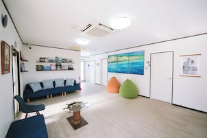 Un área de recepción con un sofá azul, una mesa de centro de vidrio y un cuadro en la pared.