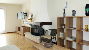 Un salon avec une cheminée, un téléviseur, une bibliothèque et un coin repas.