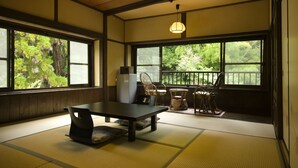 Una habitación japonesa tradicional con suelo de tatami, una mesa baja y vistas al exterior.