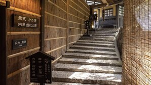 Una escalera de madera con indicaciones que señalan diferentes zonas de baño para hombres y mujeres.