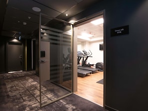 Uma academia moderna com esteiras, bicicleta ergométrica e um banco de musculação.