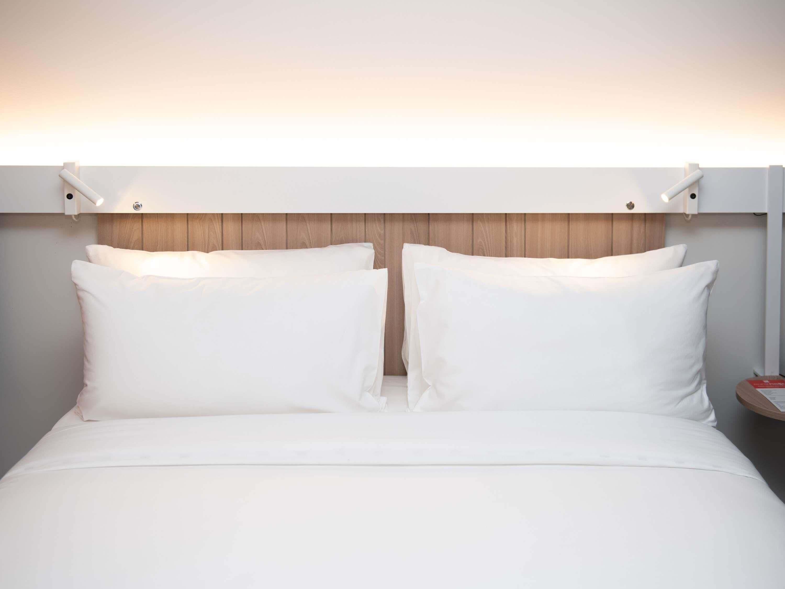 A bed with white bedding, a wooden headboard, and bedside lamps.