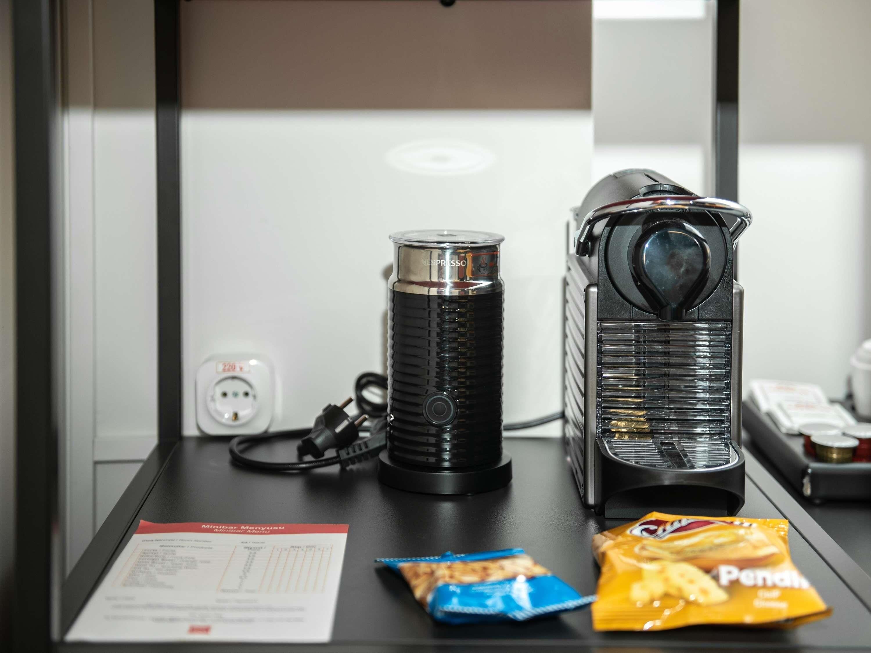 Uma máquina de café, uma chaleira e um pacote de lanches sobre a mesa.