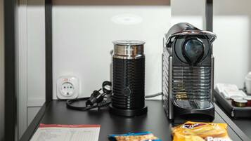 Uma máquina de café, uma chaleira e um pacote de lanches sobre a mesa.